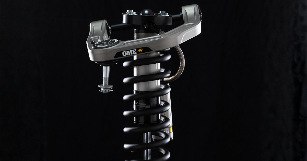 Old Man Emu Forged Billet upper control arm on a coilover shock with a braided remote reservoir line, shown on a black background